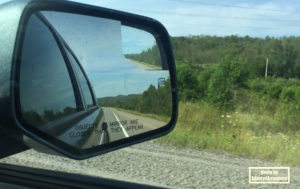 Ontario road trip - Rearview mirror of a vehicle with the road behind you.