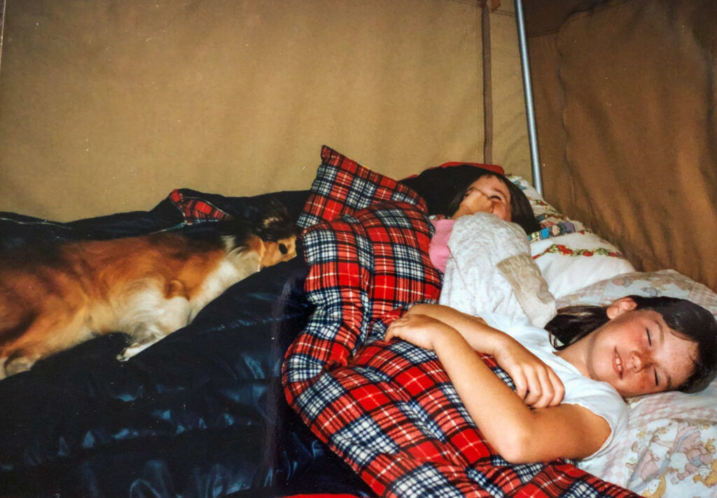 Children sleeping with dog in tent