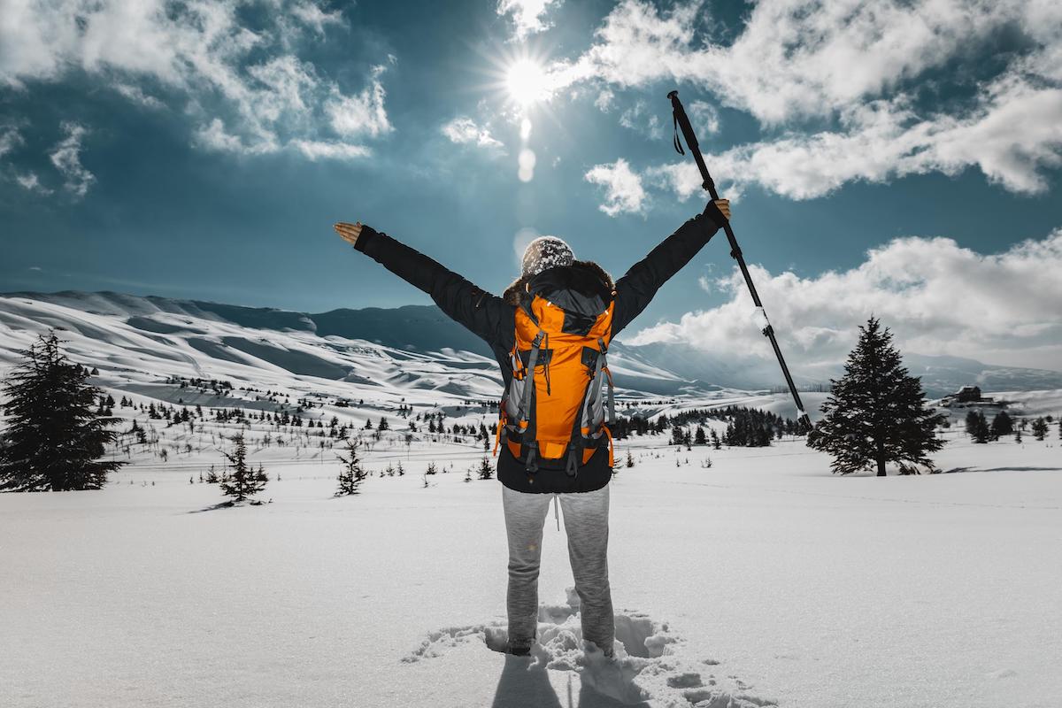 Activities Outside in Winter. Adventurous Backpacker Girl Hiking and Climbing to high mountains alone. Extreme Sports.